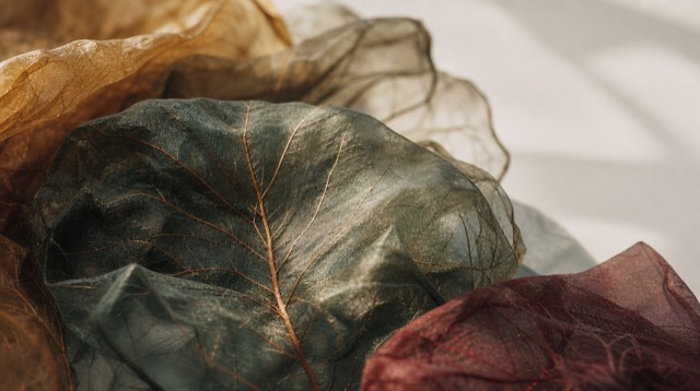 Abstract still life: a macro close-up of layered translucent silk sheets with fine copper-coloured veins, light passing through them