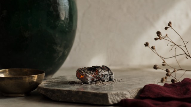 Abstract still life: a glowing ember cooling into grey ash on a stone slab