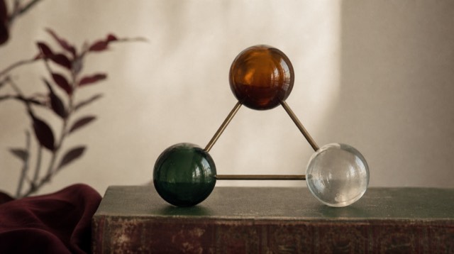 Abstract still life: three glass spheres connected by brass rods in a triangle